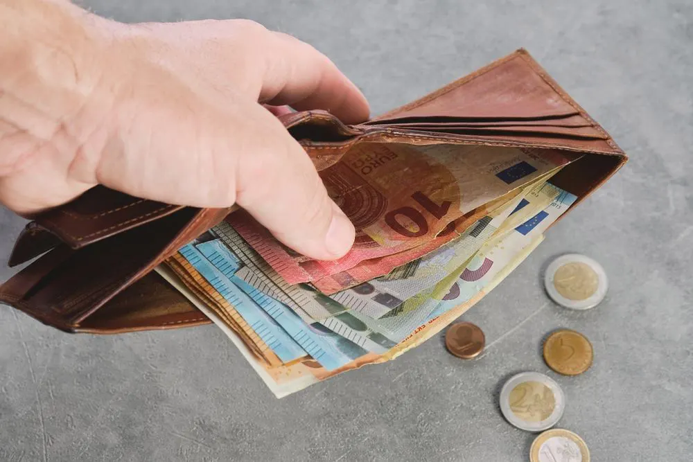 Mann hält Geldbeutel mit Euro-Scheinen in der Hand